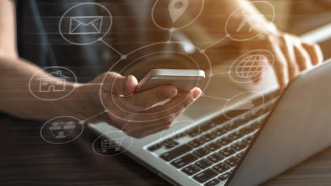 cell phone in hand with laptop